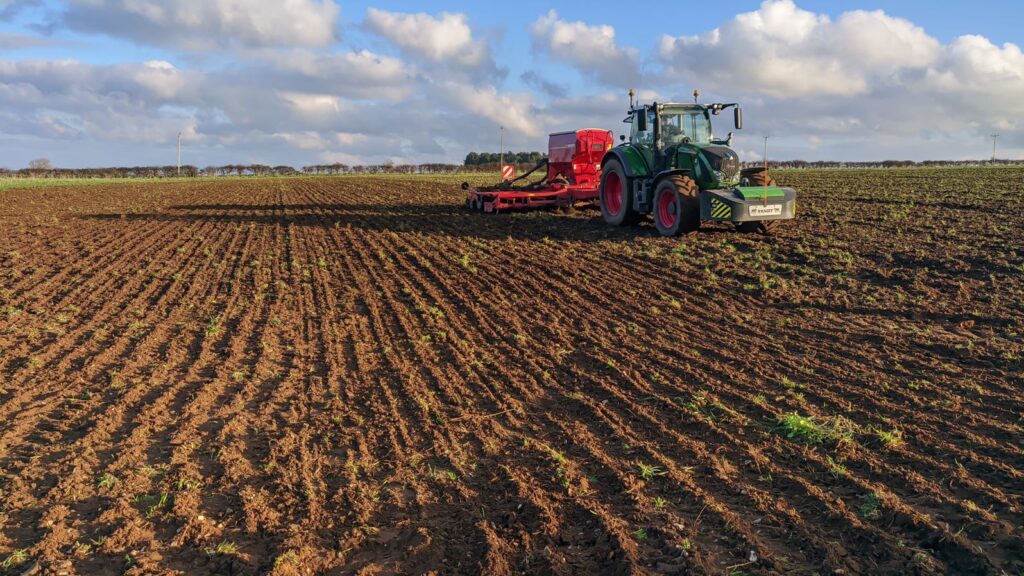 A tractor drilling wheat in a field